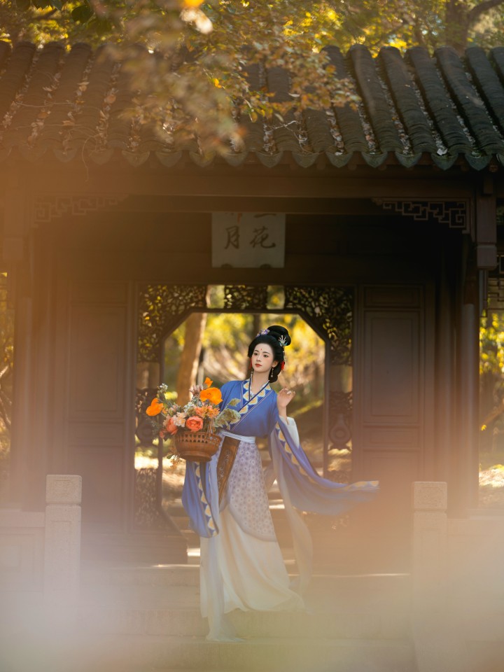 身着华服的女子在苏州园林中优雅回眸