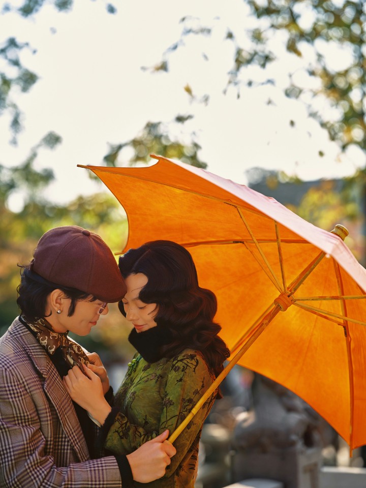 一位女士身着淡雅旗袍，在园林的月亮门旁回眸