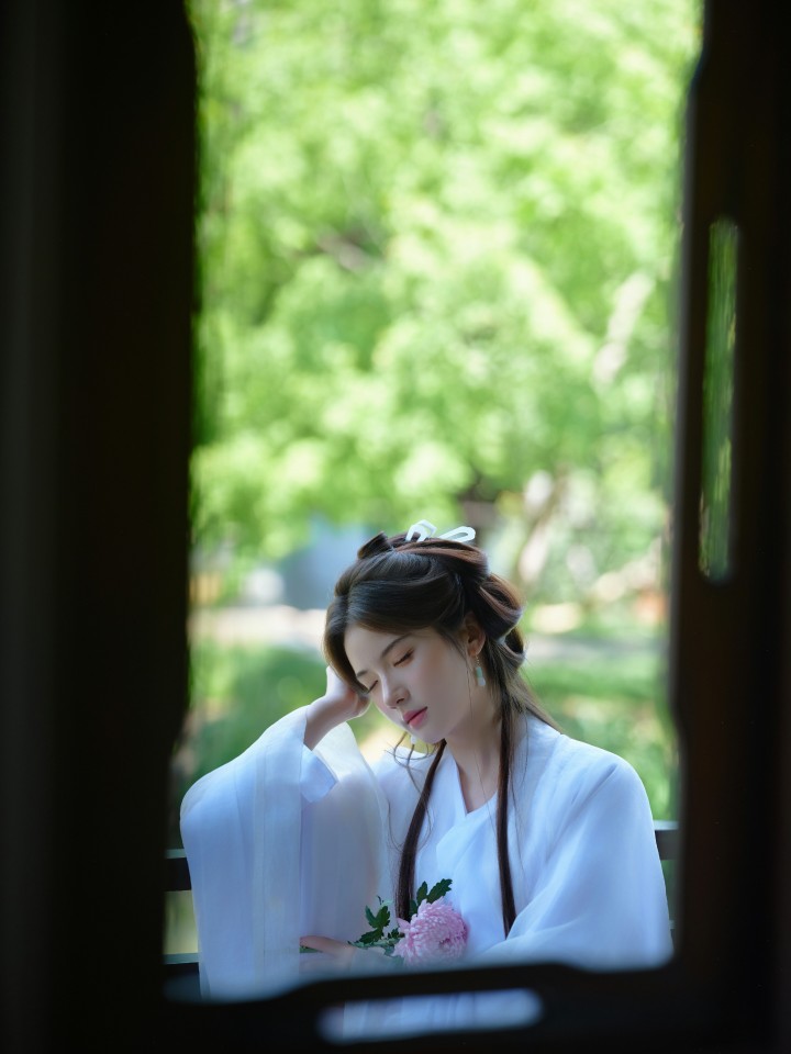 身着华服的女子在苏州园林中漫步