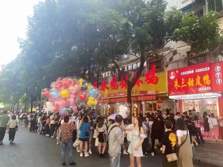 手捧甜皮鸭的顾客与朱三门店招牌合影